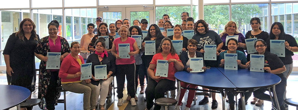 Community health workers hold up their just-earned Mental Health First Aid certificates.