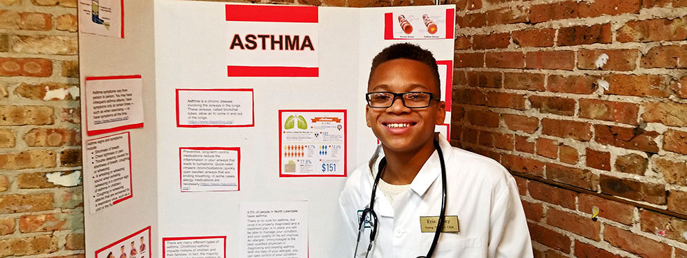 A teenage student stands beside his poster at the Young Doctors program.