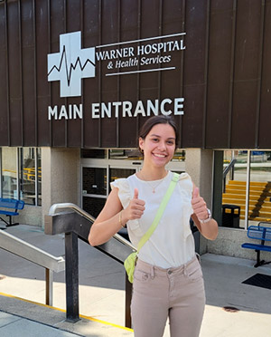 RHE participant Faith Nuss poses poses in front of Warner Hospital, where she witnessed so numerous facets of hospital care.