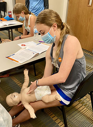 Young participant in a Safe Sitter class practices on a simulated baby.