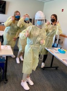 High school students donning personal protective equipment as they learn about being a nurse. 